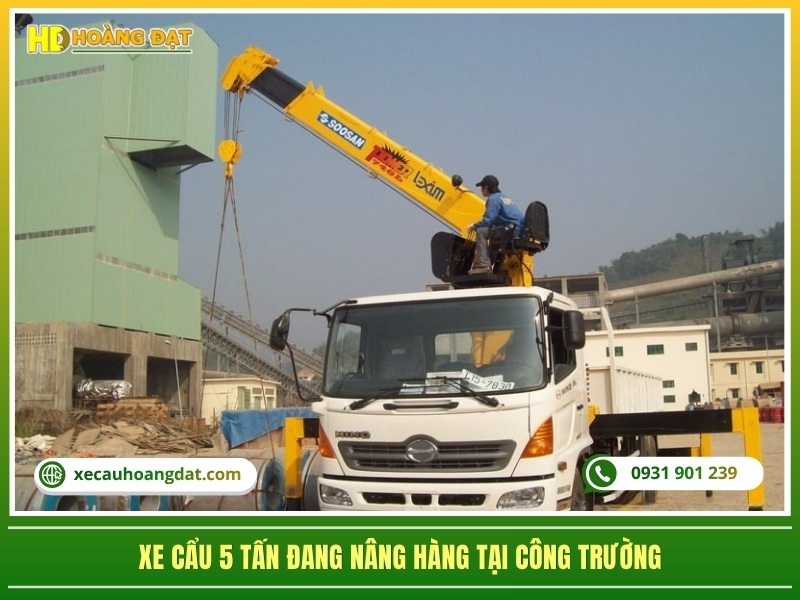 xe cẩu 5 tấn gắn trên xe tải đang nâng hàng tại công trường xây dựng